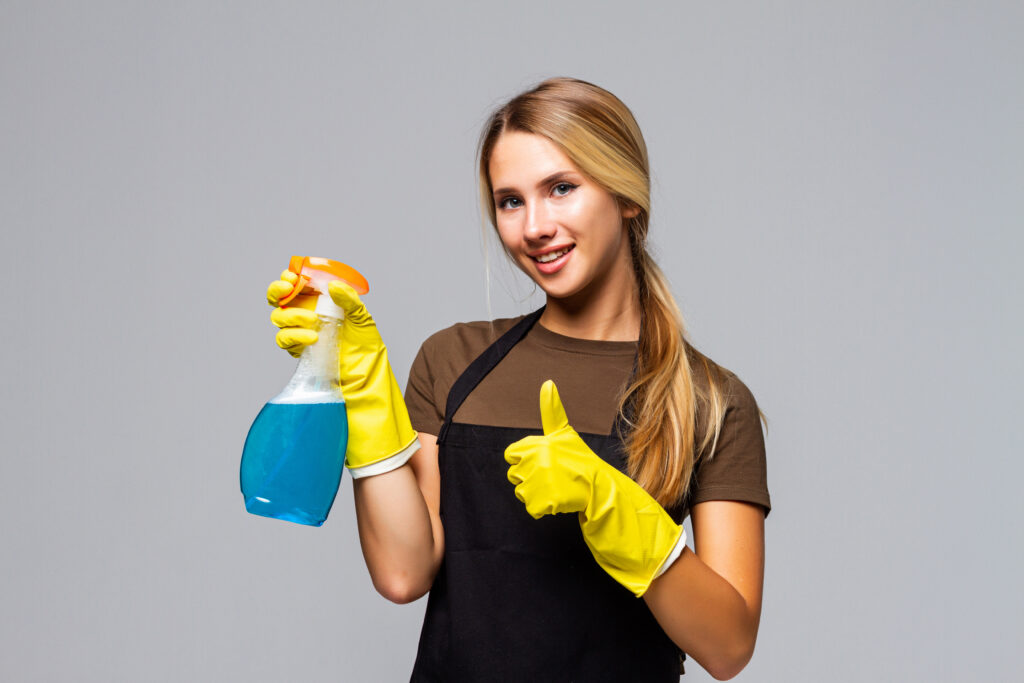 Mujer con guantes y materiales de limpieza